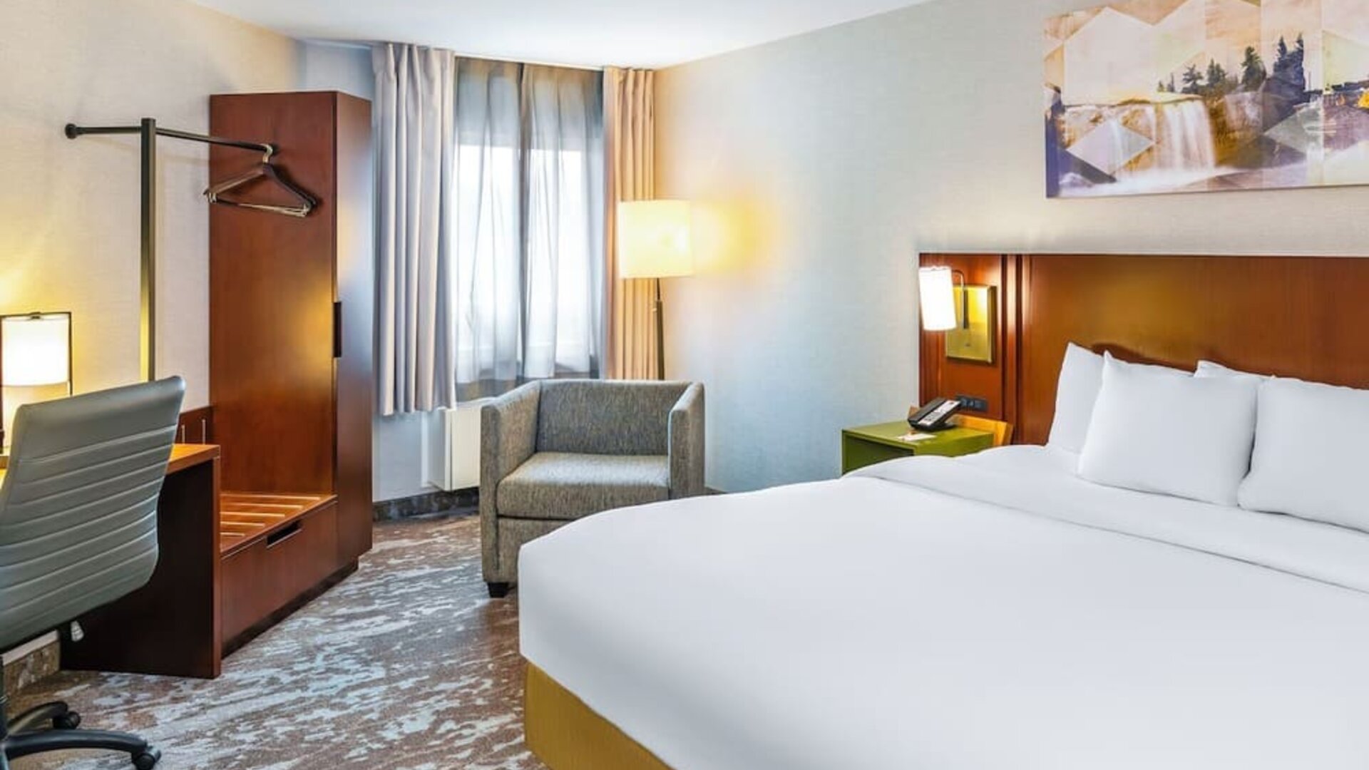 King guest room with natural light, cozy seating, and a modern workspace at Comfort Inn Sudbury East.