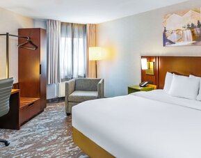 King guest room with natural light, cozy seating, and a modern workspace at Comfort Inn Sudbury East.