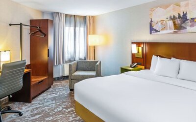 King guest room with natural light, cozy seating, and a modern workspace at Comfort Inn Sudbury East.