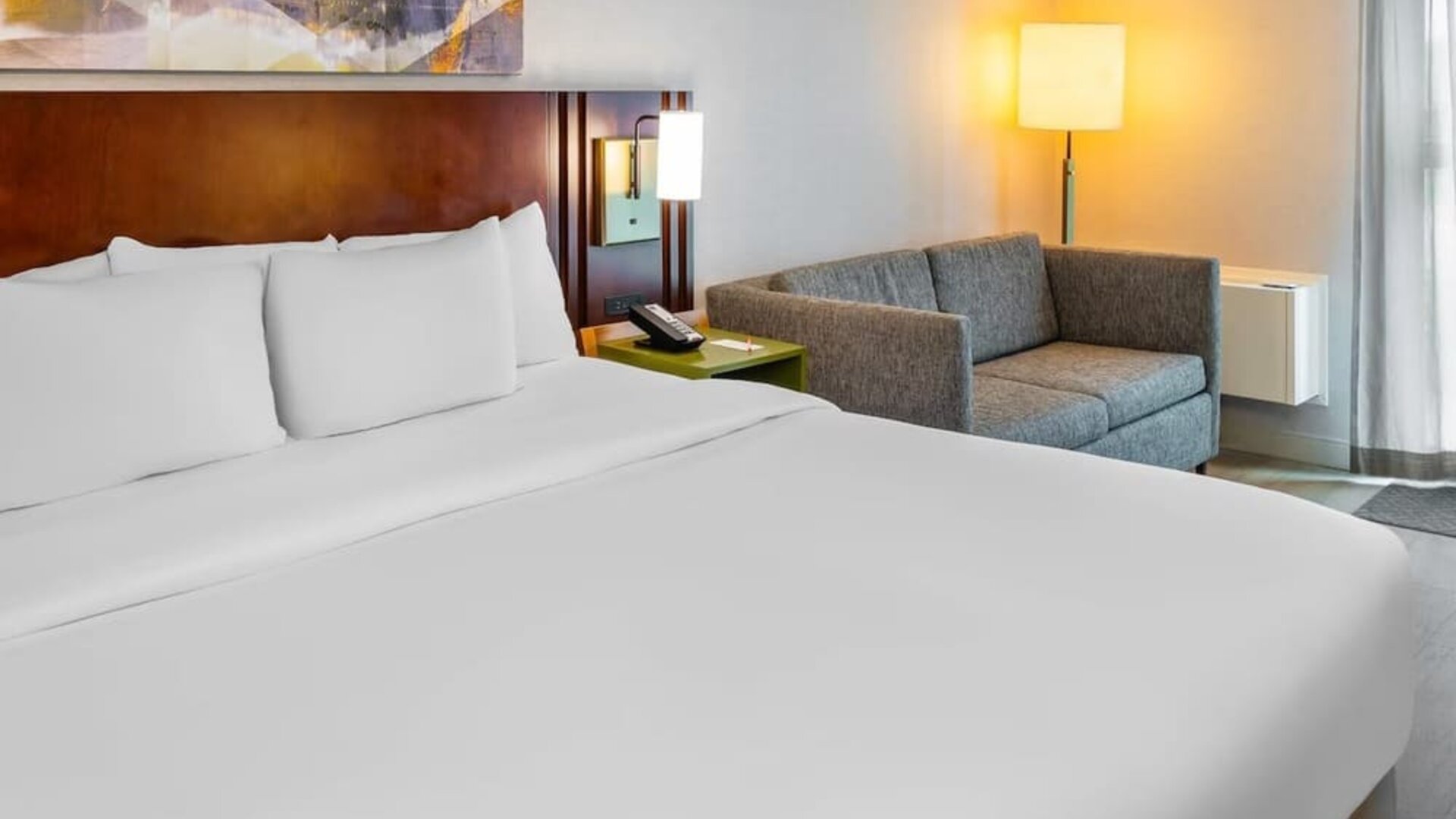 King guest room featuring plush bedding, a cozy loveseat, and modern furnishings at Comfort Inn Sudbury East.