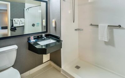 Accessible guest bathroom featuring a roll-in shower, modern vanity, and safety grab bars at Comfort Inn Sudbury East.