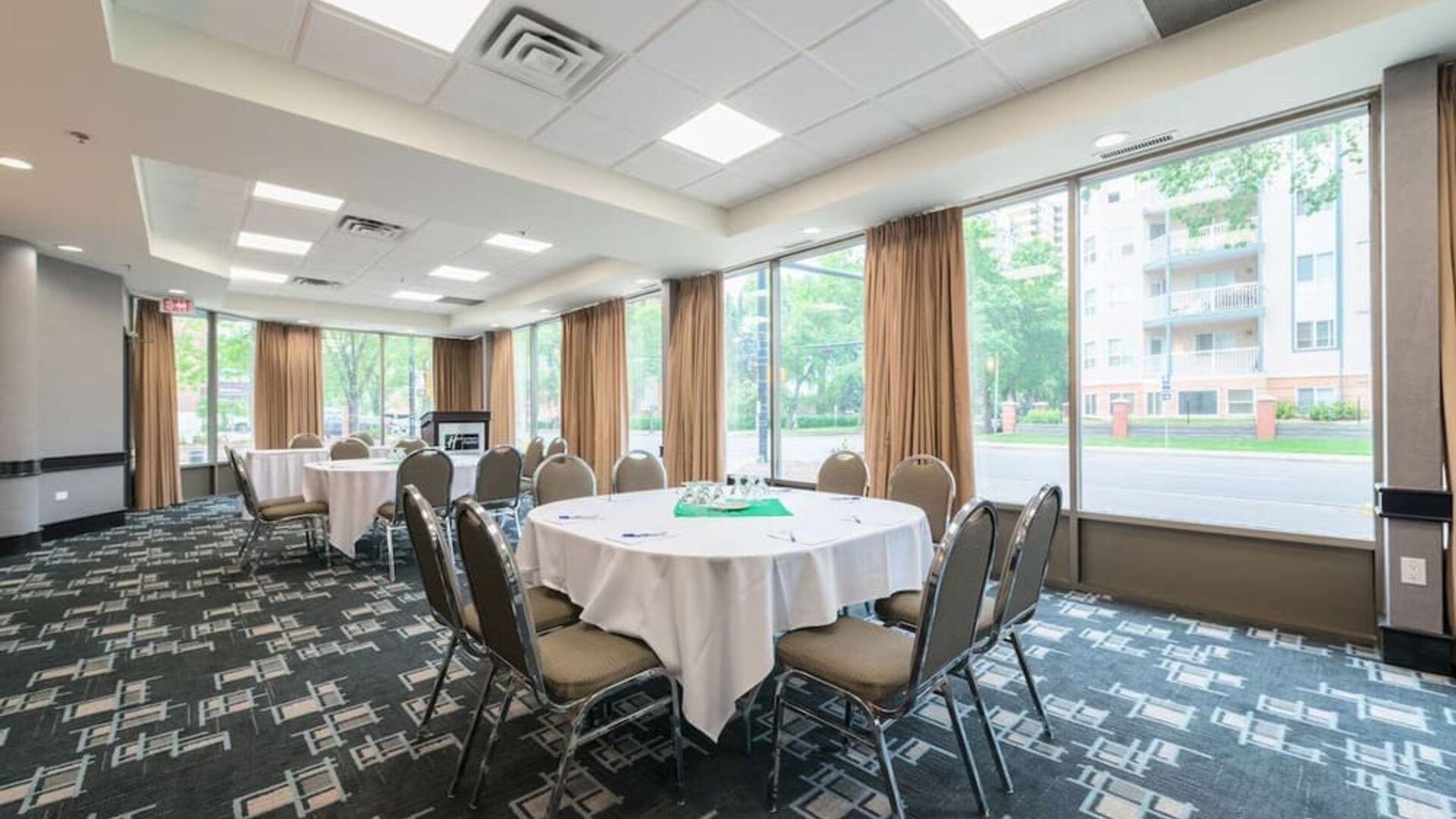 Meeting room with round tables and natural light for business events at Holiday Inn Express Edmonton Downtown, an IHG Hotel.