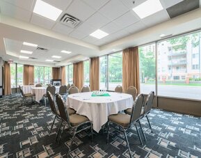Meeting room with round tables and natural light for business events at Holiday Inn Express Edmonton Downtown, an IHG Hotel.