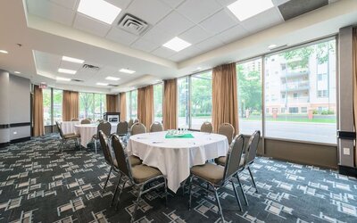 Meeting room with round tables and natural light for business events at Holiday Inn Express Edmonton Downtown, an IHG Hotel.