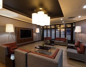 Modern hotel lobby with comfortable seating, large TV, and stylish lighting at Holiday Inn Express Edmonton Downtown, an IHG Hotel.