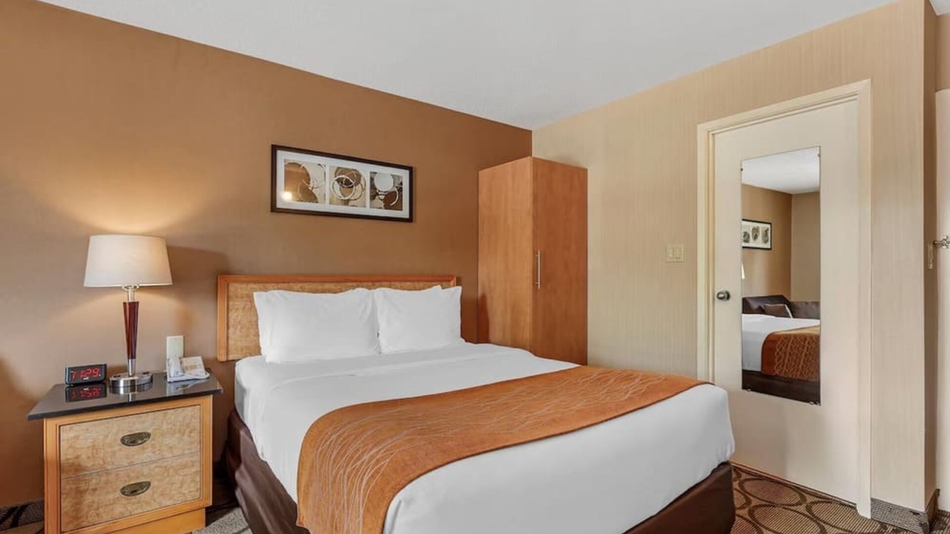 Cozy guest room with a queen bed and wardrobe at Comfort Inn Brantford.