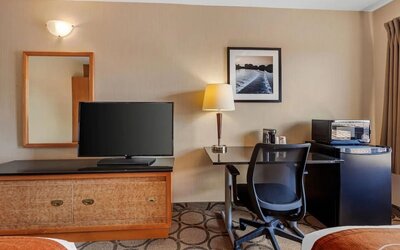 Guest room workspace with a desk, TV, microwave, and mini fridge at Comfort Inn Brantford.