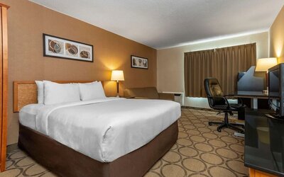 Spacious king guest room with a work desk and seating area at Comfort Inn Sept-Iles.