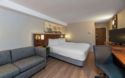 Spacious king guest room with a sofa and work desk at Comfort Inn Sault Ste. Marie.