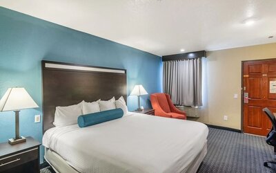 Spacious guest room with a king bed and armchair at Glenridge Inn Glendale Pasadena.