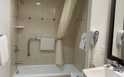 Accessible guest bathroom with a bathtub and shower at Glenridge Inn Glendale Pasadena.