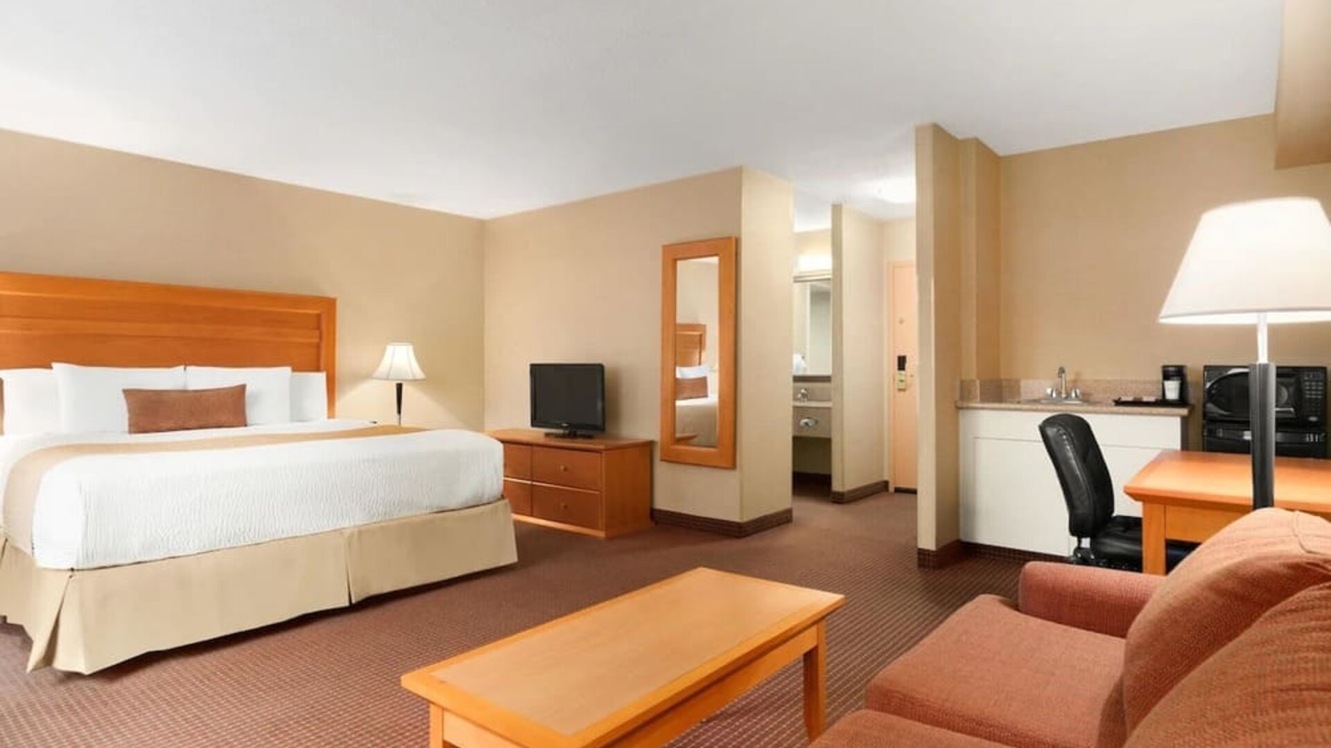 Spacious guest room with a king bed, seating area, and work desk at Days Inn Edmonton Downtown.