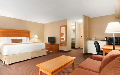 Spacious guest room with a king bed, seating area, and work desk at Days Inn Edmonton Downtown.