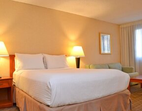Spacious guest room with a king bed, sofa, and seating area at Amenida Residences.