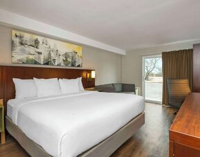 King guest room with a sofa, work desk, and window seating area at Comfort Inn Brossard.