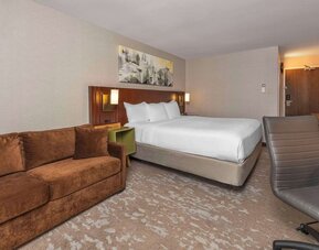 Spacious guest room with a king bed, sofa, and work desk at Comfort Inn Brossard.