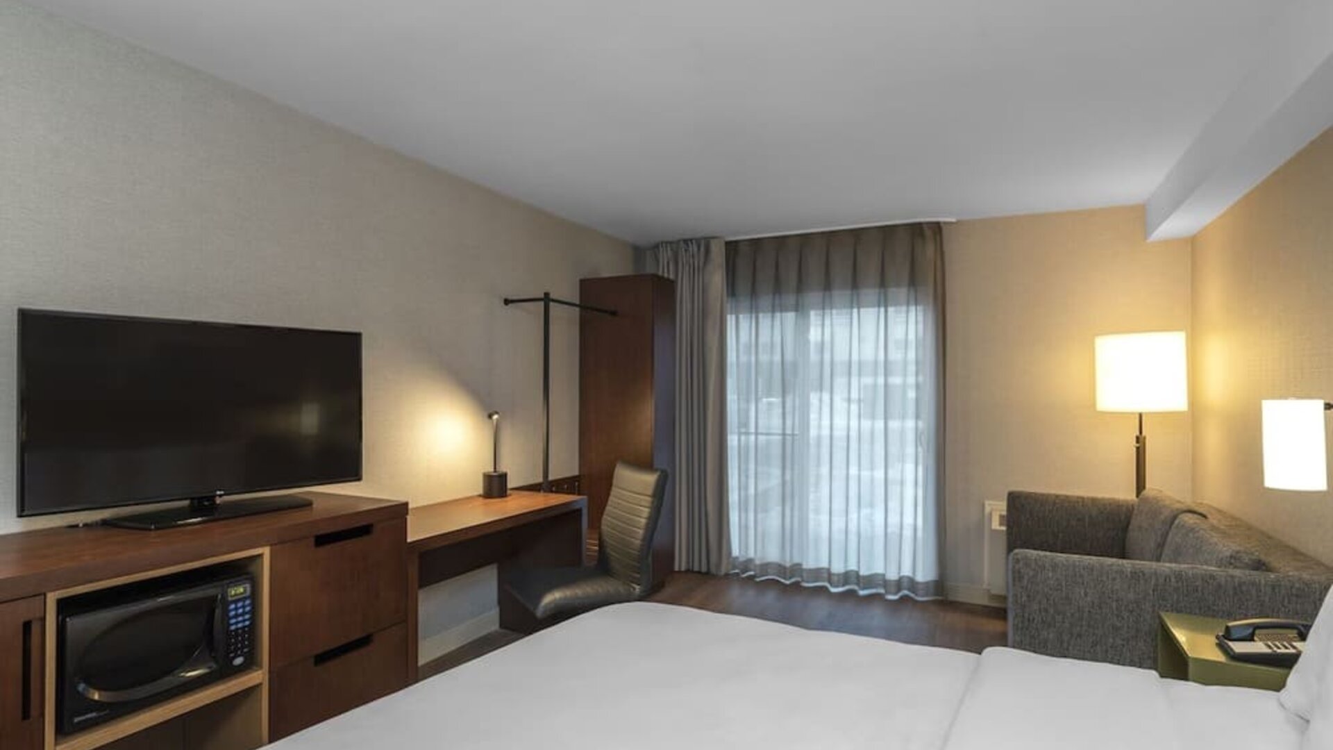 Guest room with a king bed, sofa, work desk, and flat-screen TV at Comfort Inn Ottawa East.
