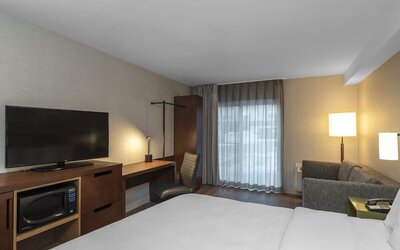 Guest room with a king bed, sofa, work desk, and flat-screen TV at Comfort Inn Ottawa East.
