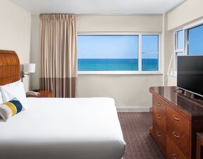 Guest room with a king bed and panoramic ocean view at Sherry Frontenac Oceanfront Hotel.