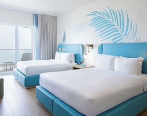 Guest room with two queen beds and a private balcony at Sherry Frontenac Oceanfront Hotel.