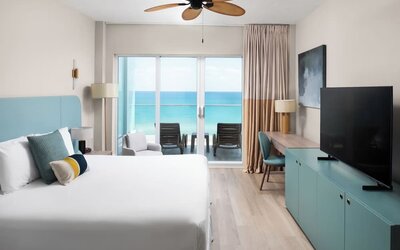 Oceanfront guest room with a private balcony and king bed at Sherry Frontenac Oceanfront Hotel.