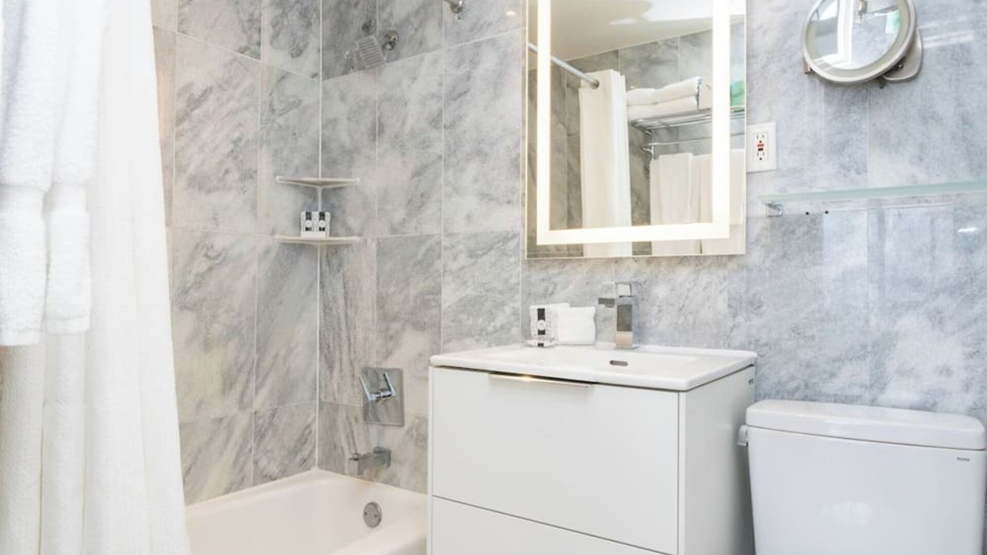 Guest bathroom with a bathtub and marble-style tile walls at Sherry Frontenac Oceanfront Hotel.