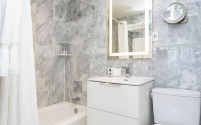 Guest bathroom with a bathtub and marble-style tile walls at Sherry Frontenac Oceanfront Hotel.