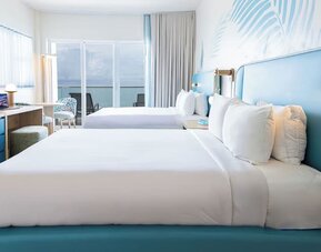 Oceanfront guest room with two queen beds and balcony access at Sherry Frontenac Oceanfront Hotel.