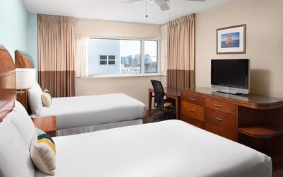 Guest room with two queen beds and tropical décor at Sherry Frontenac Oceanfront Hotel.