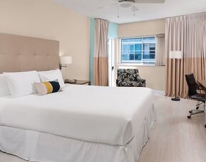 Spacious guest room with a king bed and work desk at Sherry Frontenac Oceanfront Hotel.