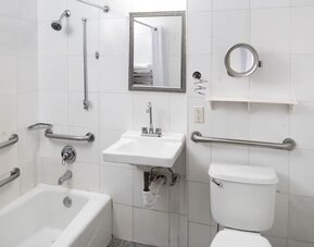 Accessible guest bathroom with grab bars and a bathtub at Sherry Frontenac Oceanfront Hotel.