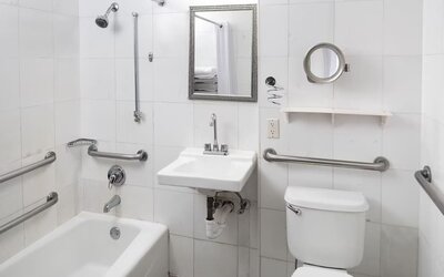 Accessible guest bathroom with grab bars and a bathtub at Sherry Frontenac Oceanfront Hotel.