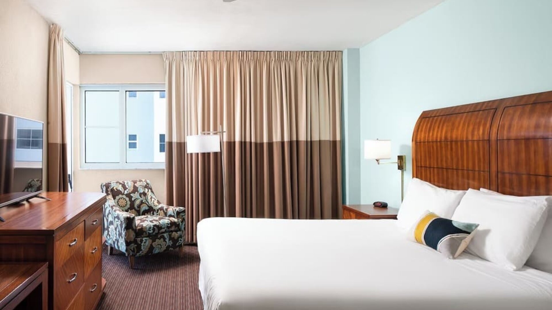 Guest room with a king bed and armchair at Sherry Frontenac Oceanfront Hotel.