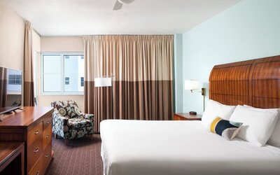 Guest room with a king bed and armchair at Sherry Frontenac Oceanfront Hotel.