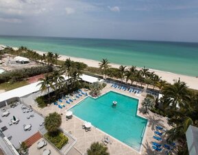 Elevated view of the outdoor pool and beachfront at Sherry Frontenac Oceanfront Hotel.Oceanfront guest room with two beds, workspace, and private balcony at Sherry Frontenac Oceanfront Hotel.