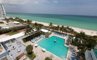 Elevated view of the outdoor pool and beachfront at Sherry Frontenac Oceanfront Hotel.Oceanfront guest room with two beds, workspace, and private balcony at Sherry Frontenac Oceanfront Hotel.