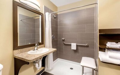Accessible guest bathroom with a roll-in shower at La Quinta Inn & Suites By Wyndham Oshawa.