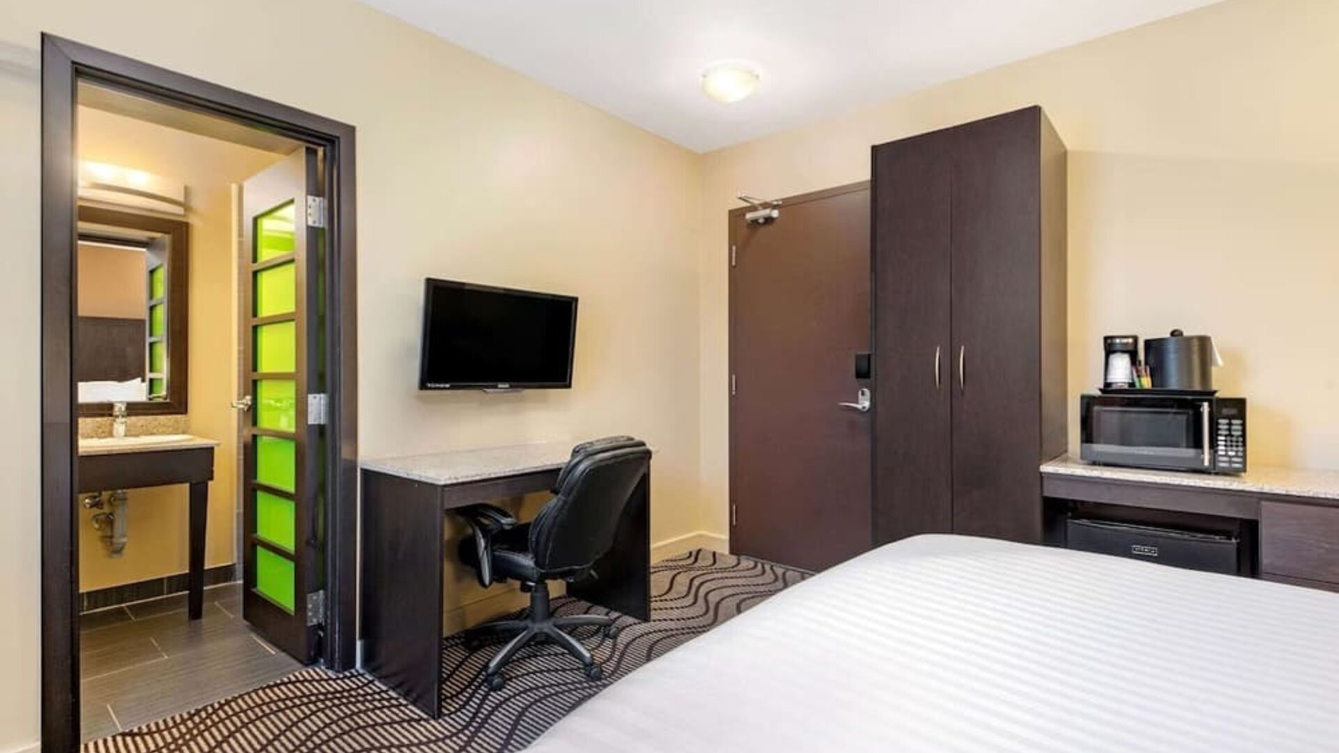 Guest room with a workspace, microwave, and mini fridge at La Quinta Inn & Suites By Wyndham Oshawa.