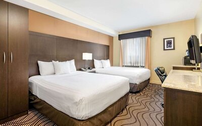 Guest room with two queen beds and bedside table at La Quinta Inn & Suites By Wyndham Oshawa.