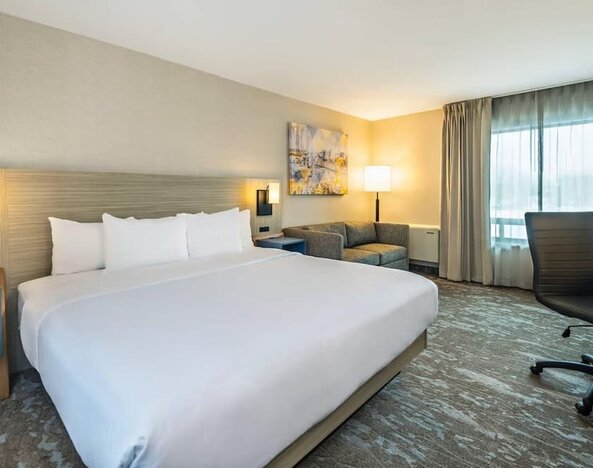Spacious guest room with a king bed and seating area at Comfort Inn Saskatoon.
