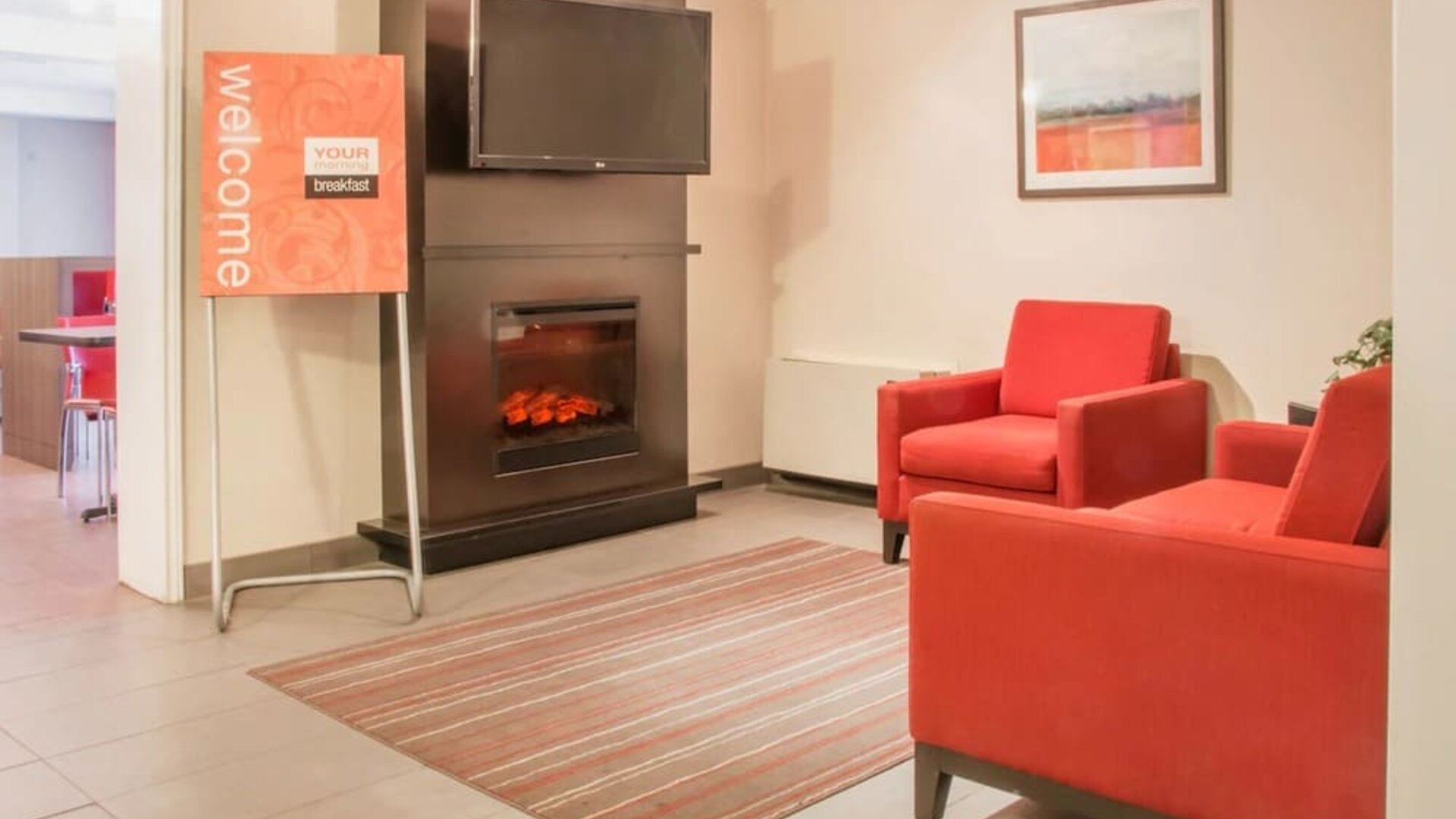 Lobby seating area with a fireplace and lounge chairs at Comfort Inn Saskatoon.