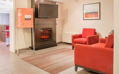 Lobby seating area with a fireplace and lounge chairs at Comfort Inn Saskatoon.