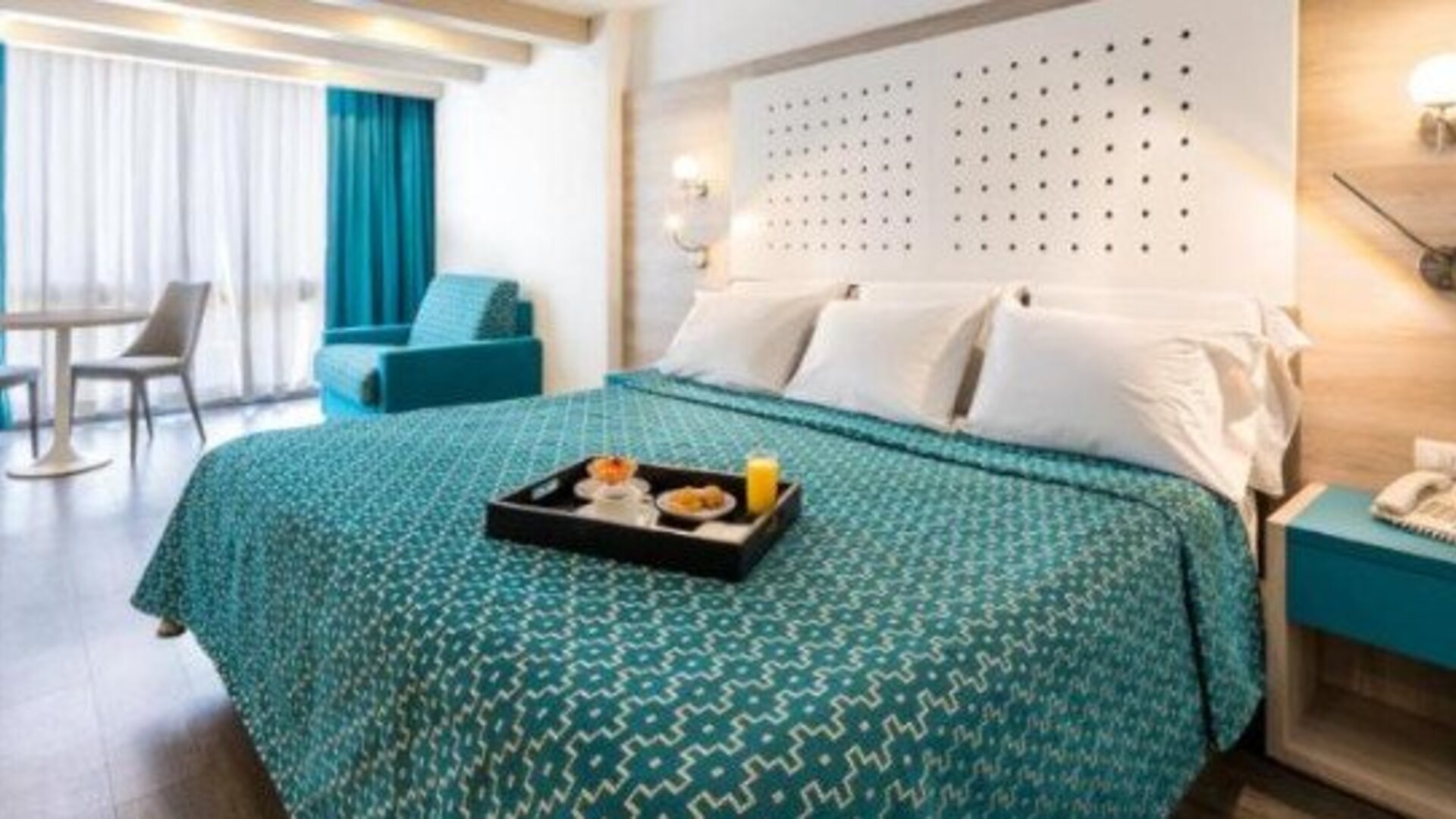 King guest room with breakfast tray, seating area and large windows with full-length curtains at Hotel Casa Blanca.