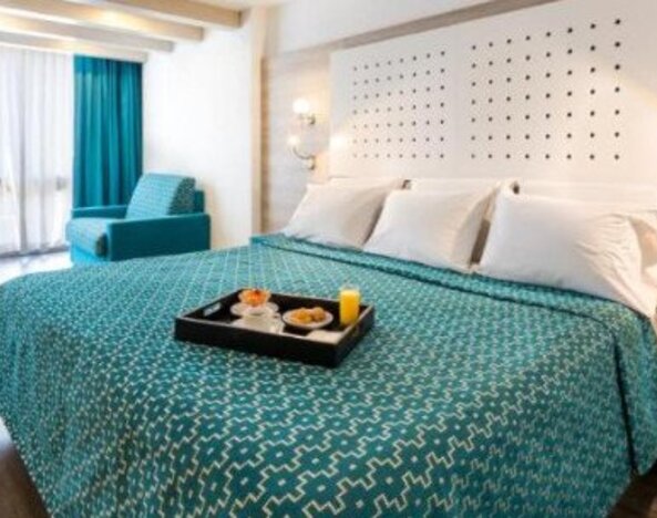 King guest room with breakfast tray, seating area and large windows with full-length curtains at Hotel Casa Blanca.