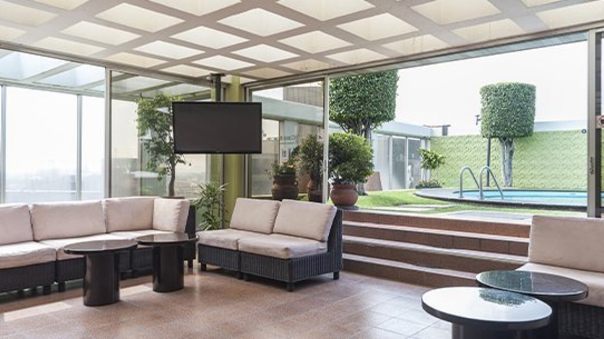 Indoor lounge with cushioned seating, floor-to-ceiling windows and views of the outdoor pool at Hotel Casa Blanca.