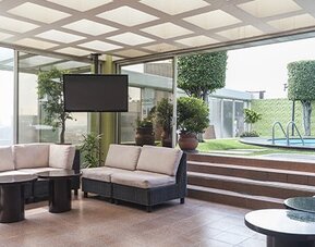 Indoor lounge with cushioned seating, floor-to-ceiling windows and views of the outdoor pool at Hotel Casa Blanca.