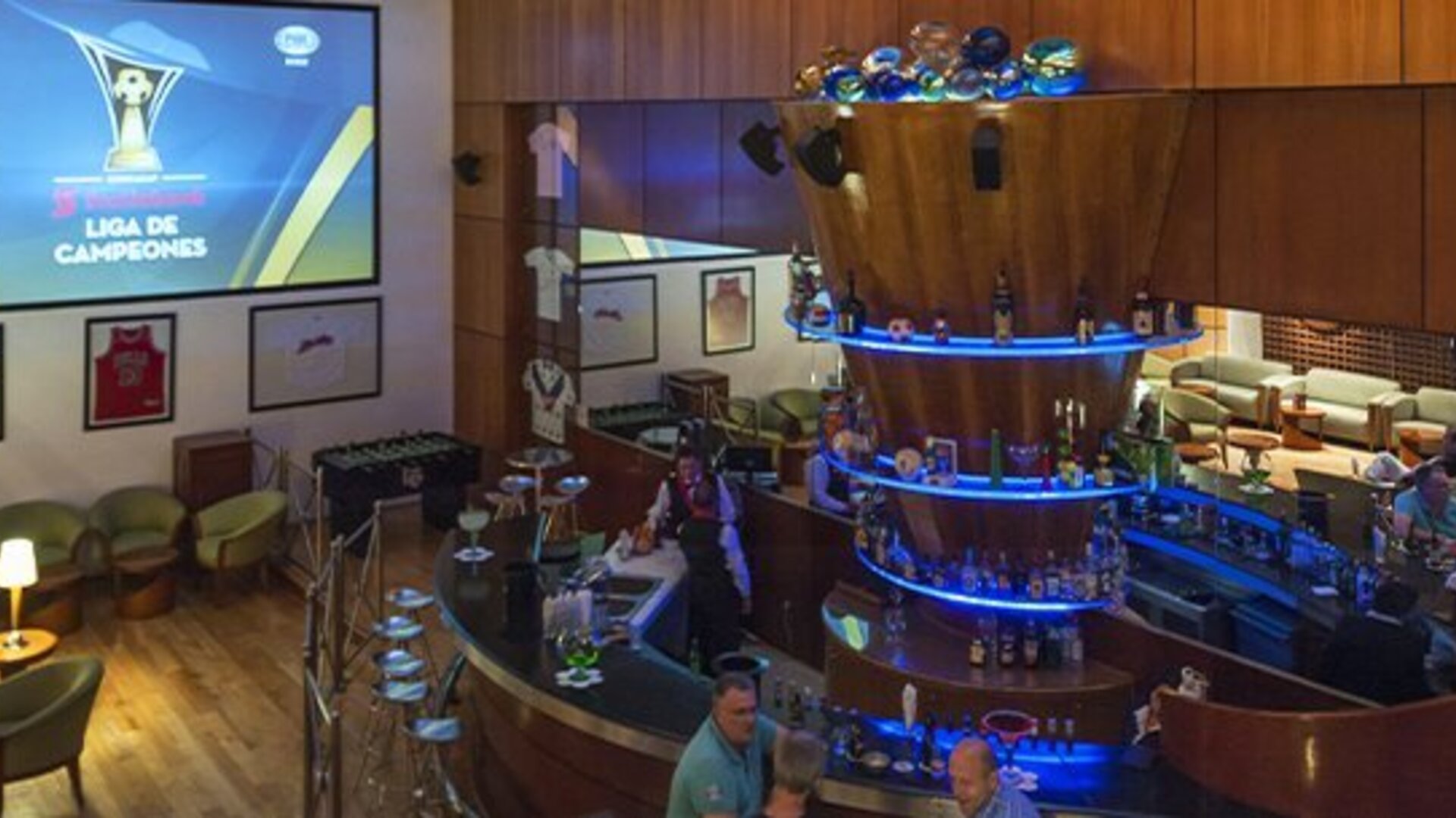 Sports bar with circular illuminated bar, lounge seating and large projection screen at Hotel Casa Blanca.