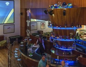 Sports bar with circular illuminated bar, lounge seating and large projection screen at Hotel Casa Blanca.