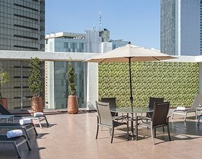 Rooftop terrace with sun loungers, outdoor seating and surrounding city skyline views at Hotel Casa Blanca.