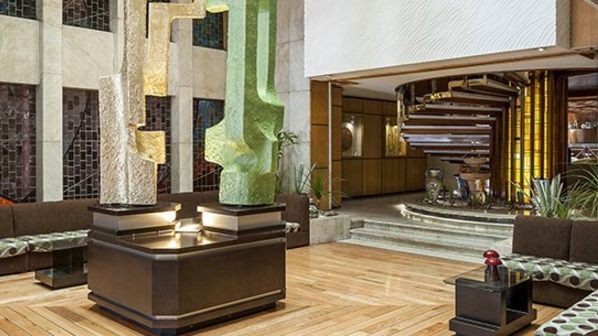 Modern hotel lobby with decorative sculptures, wood flooring and cushioned seating areas at Hotel Casa Blanca.